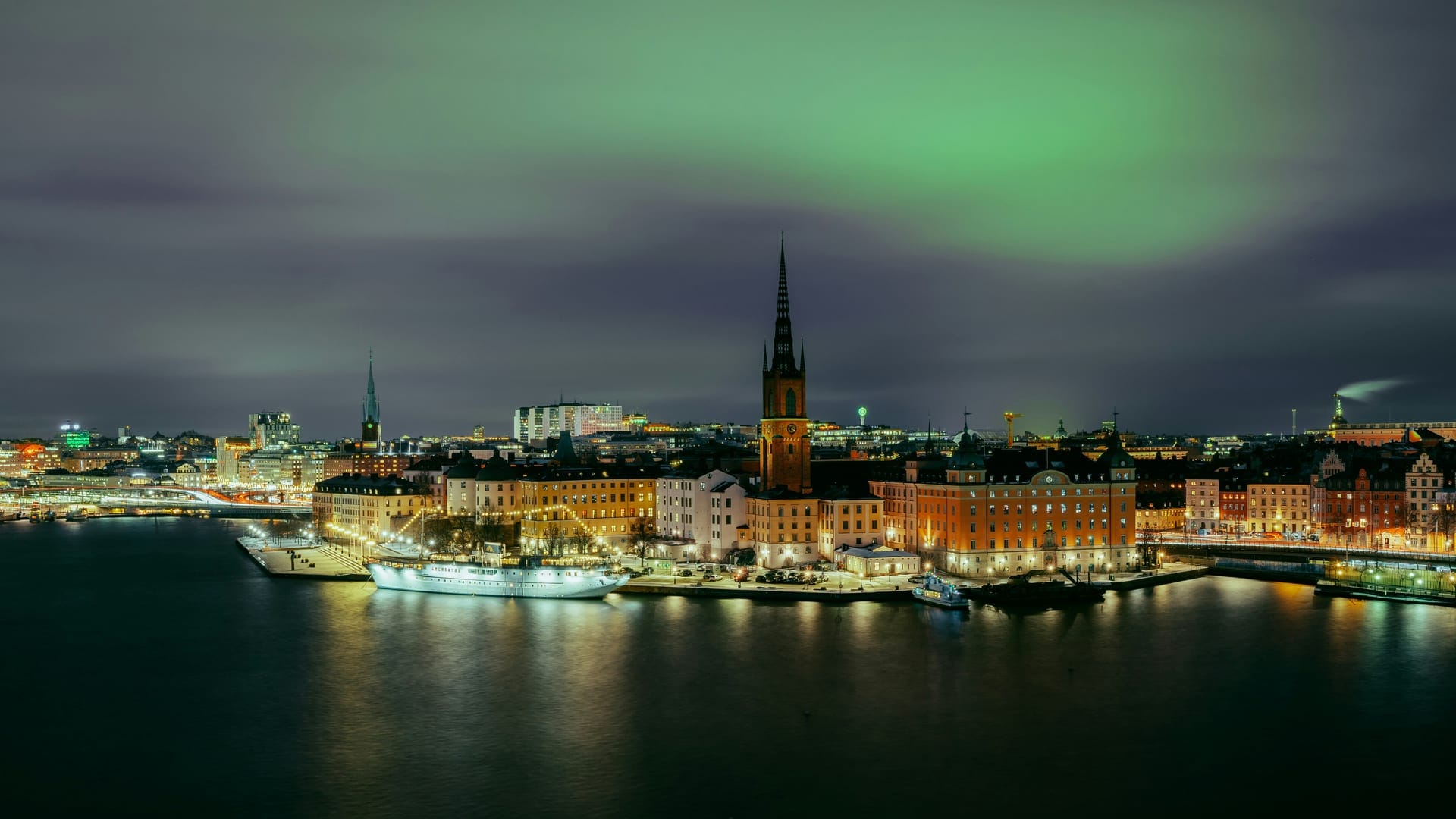 Stockholms vattenfront i svartvitt nattpanorama med kyrkspira och stadssilhuett
